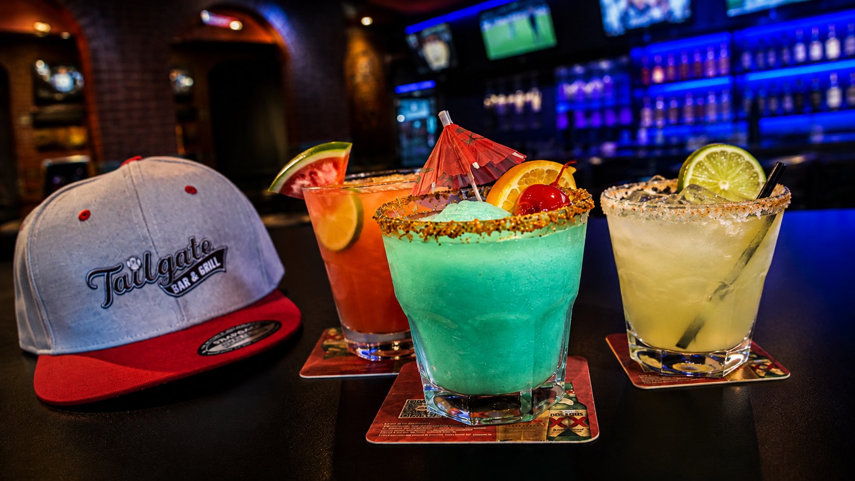 Three house cocktails and a Tailgate hat on the bar