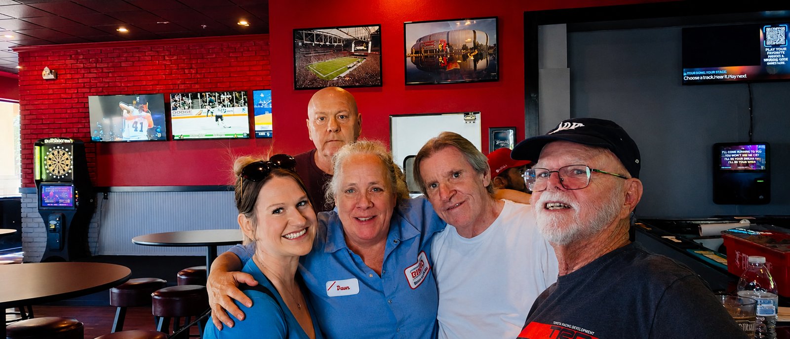 The Tailgate crew together in front of the stadium wall