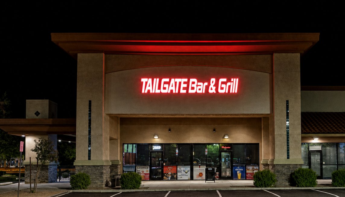 Tailgate Bar & Grill storefront at night, neon sign glowing